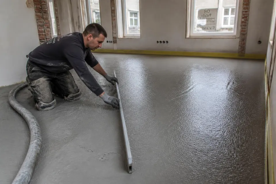 Vloerspecialist vlakt verse Isopact schuimbeton af met een rei tijdens een verbouwing